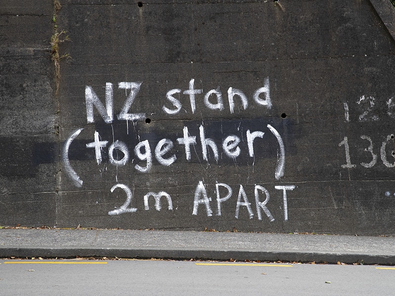 covid19_graffiti_glenmore.jpg Graffiti on a concrete wall beside a road. It says "Stand Together (2m apart)"