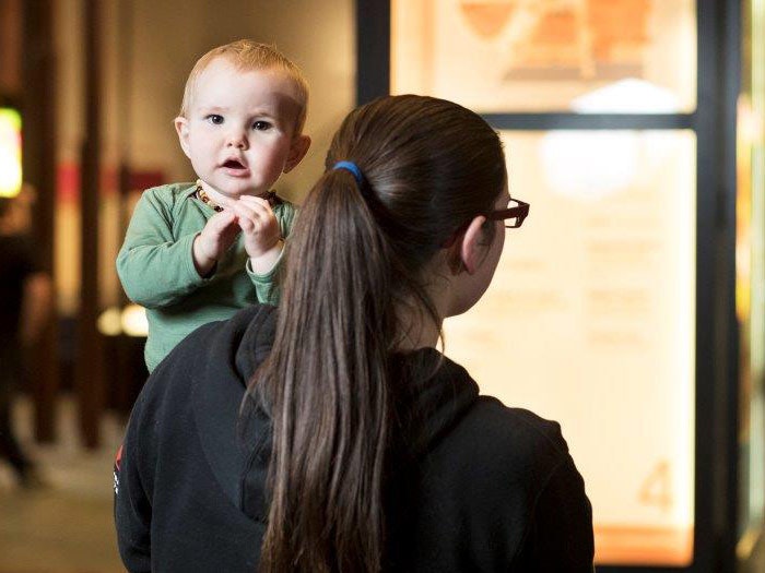 Mother checking wayfinding map, 2016. Photograph by Mike O'Neill. Te Papa Mother and baby