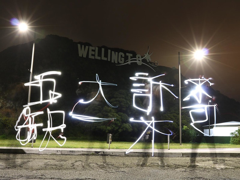 Gift of We are Kiwi Hong Kongers, 2021. CC 0. Te Papa (GH025676) A photo of someone writing Chinese using light outside in the dark