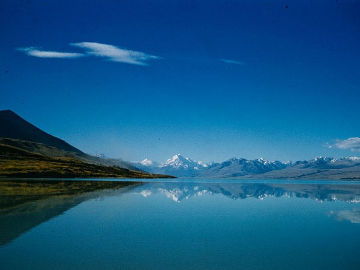 Brian Brake, Lakes. Lake Pukaki, 1960s-1980s, Canterbury. Gift of Mr Raymond Wai-Man Lau, 2001. Te Papa (CT.030312) Photo of Lake Pukaki, with mirror-like water, and a view or Aoraki Mt Cook in the distance