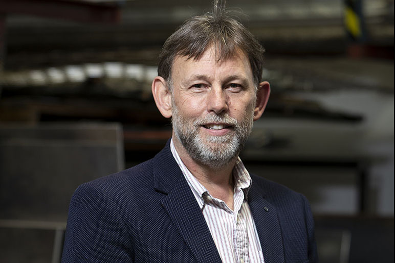 A head and shoulders photo of a bearded man in a dark suit jacket.