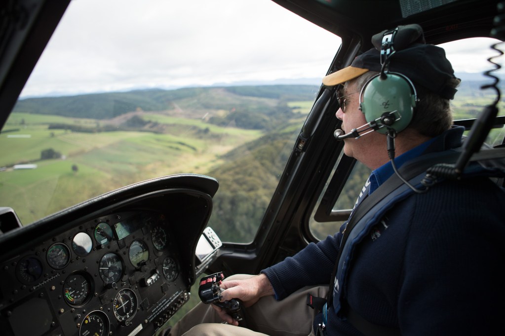 A man flies a helicopter over Solander Island