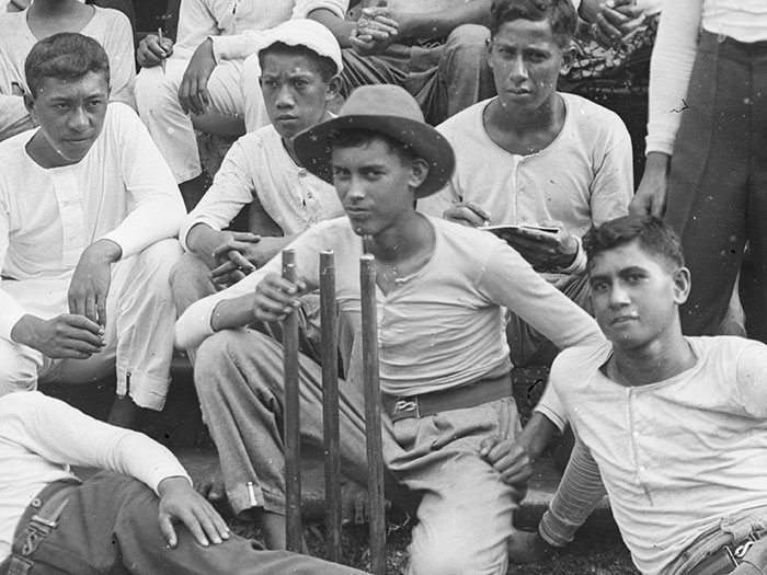 Boys sit holding a cricket wicket