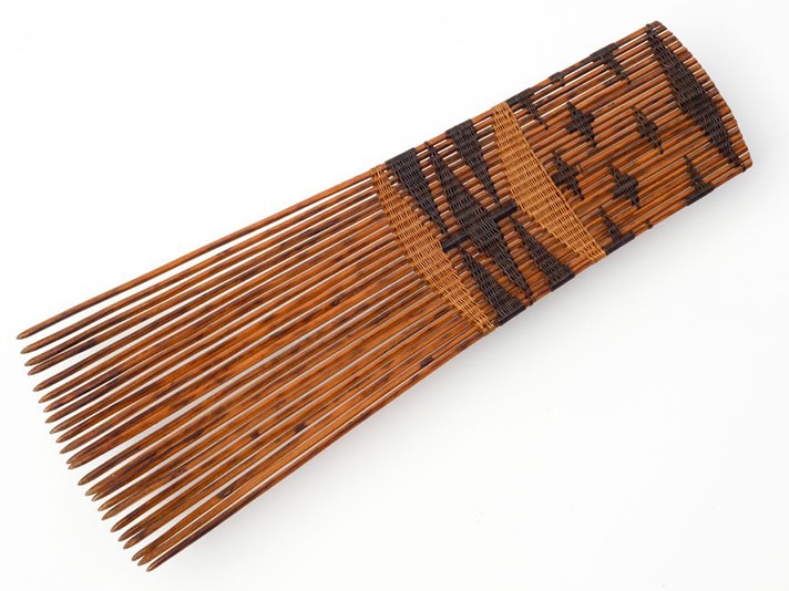 Helu (head comb), maker unknown, palm leaf. Oldman Collection. Gift of the New Zealand Government, 1992. Te Papa (OL002231) A brown wooden-looking ceremonial comb on a pale grey surface