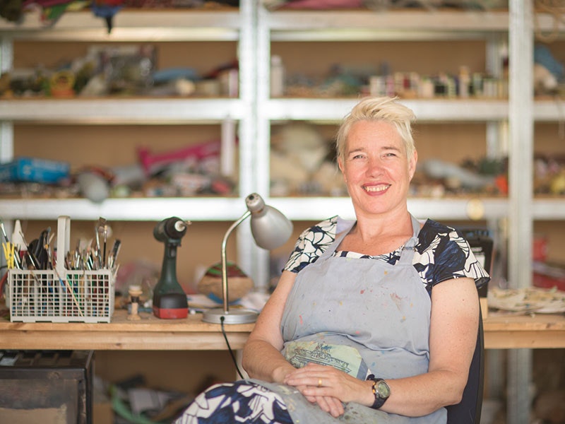 lisa-walker-studio-800x600.jpg Lisa Walker sits in her studio, with shelving behind her full of materials