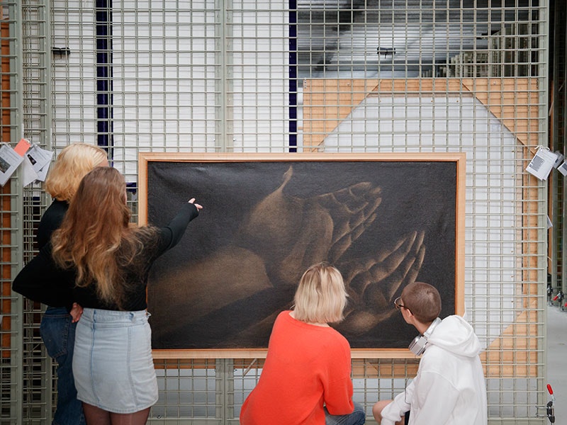 Students from Wellington High School look at Tony Fomison, Study of hands on page 235 of "Roxburgh's Common Skin Diseases" 12th edition 1961, 1971, oil on hessian. Te Papa (1997-0007-1). Photo by Kate Whitley. Te Papa Group of teenagers look at a painting hanging on a rack in the painting store room