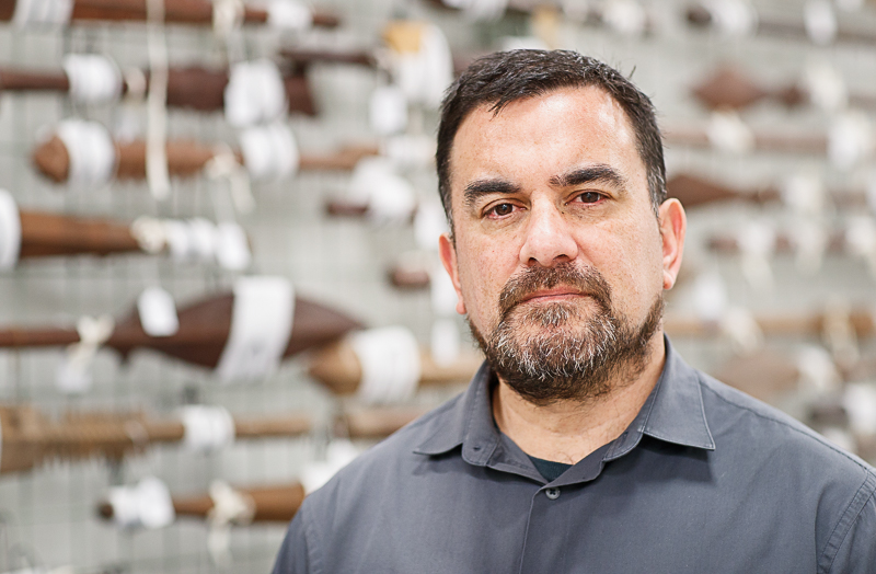 Sean Mallon stands in front of wall of Pacific collection items