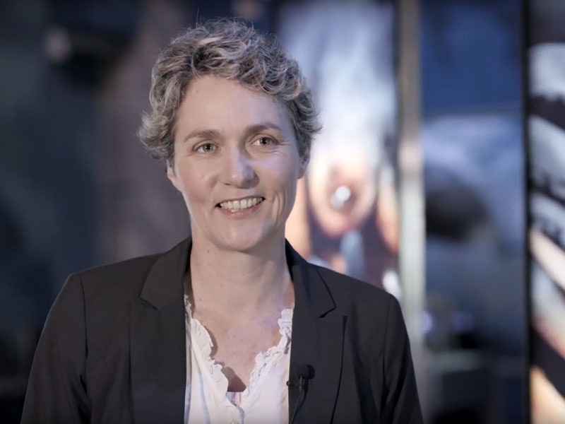 Susan Waugh Head and shoulders of a woman smiling at someone off camera.