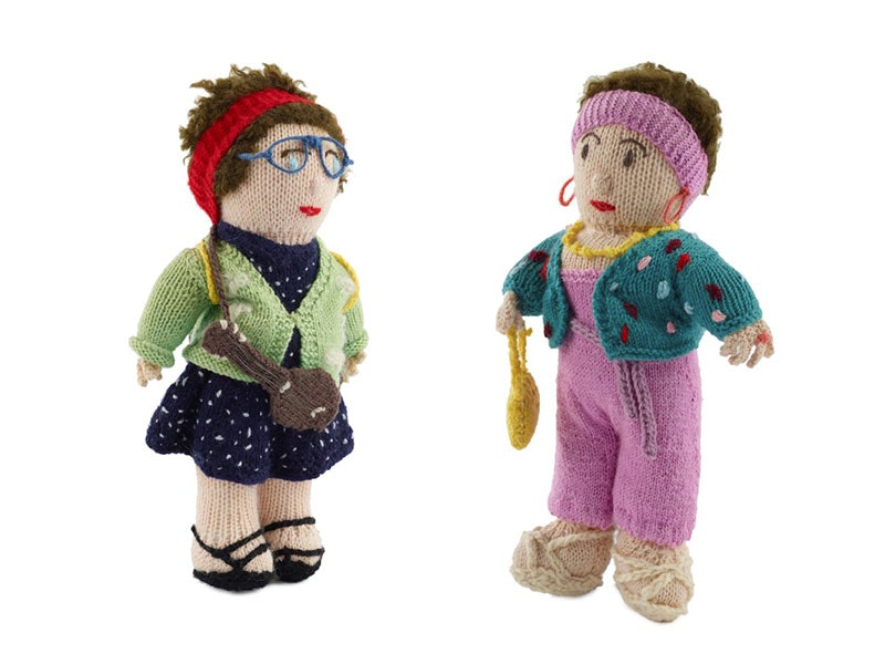 Camp Leader and Camp Mother knitted dolls, about 1999, New Zealand, maker unknown. Gift of Lynda and Jools Topp, 2000. Te Papa (GH007984 and GH007985) Two knitted dolls. Left: A woman with a red headband, wearing glasses, in a blue dress with white polkadots and a green cardigan. On the right: A woman in pink headband and dungarees with turquoise cardigan and yellow handbag
