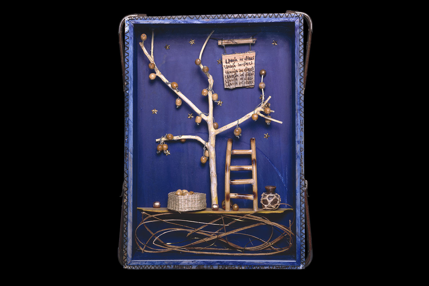 A blue box containing a wooden tree with apples, a ladder to climb to the branches, a basket for the apples, and a sign repeating uno/una in dieci (Italian for one in ten)