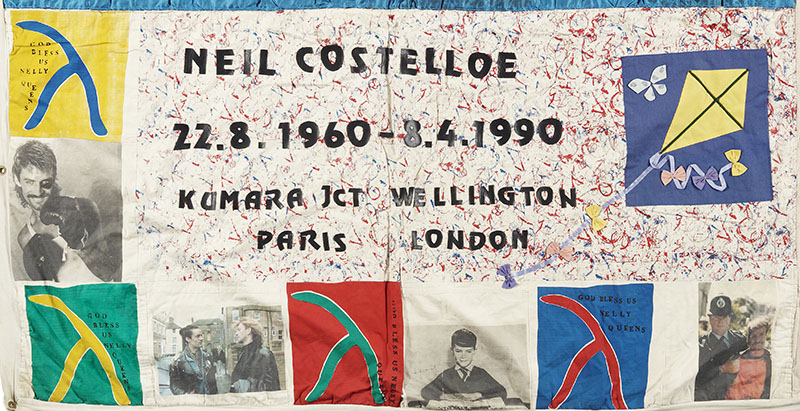 A panel from the NZ Aids Memorial Quilt. It contains multiple photos as well as four signs of different colours saying ‘God bless Welly queens’