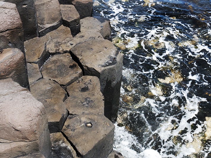 Basalt columns in Ohira Bay, Rēkohu Chatham Islands, 2019. Photo by Jane Harris Basalt columns that are mostly five-sided by the sea which has a lot of seaweed and foam in it
