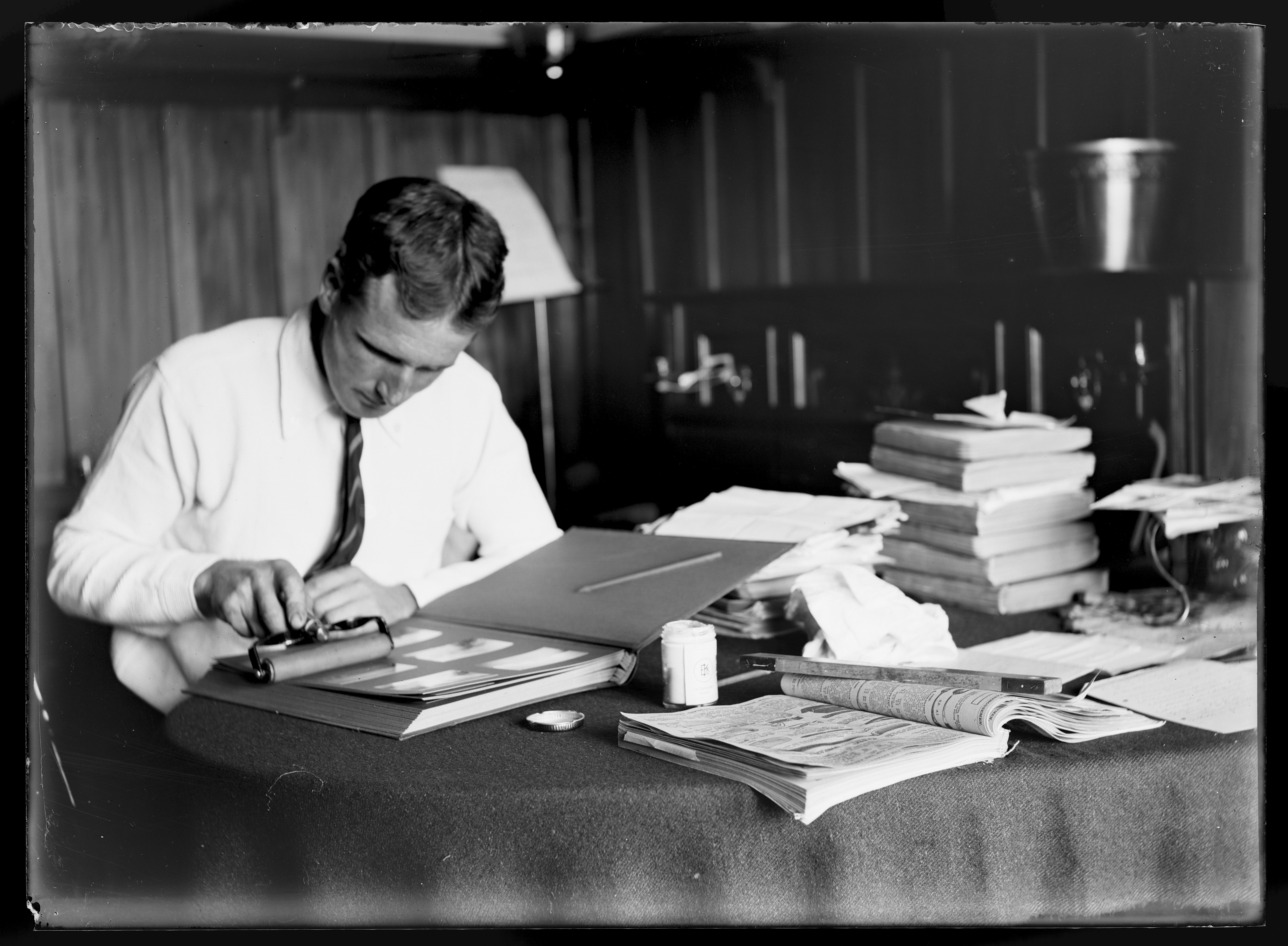 Black and white photo of a man putting a photo in a photo album