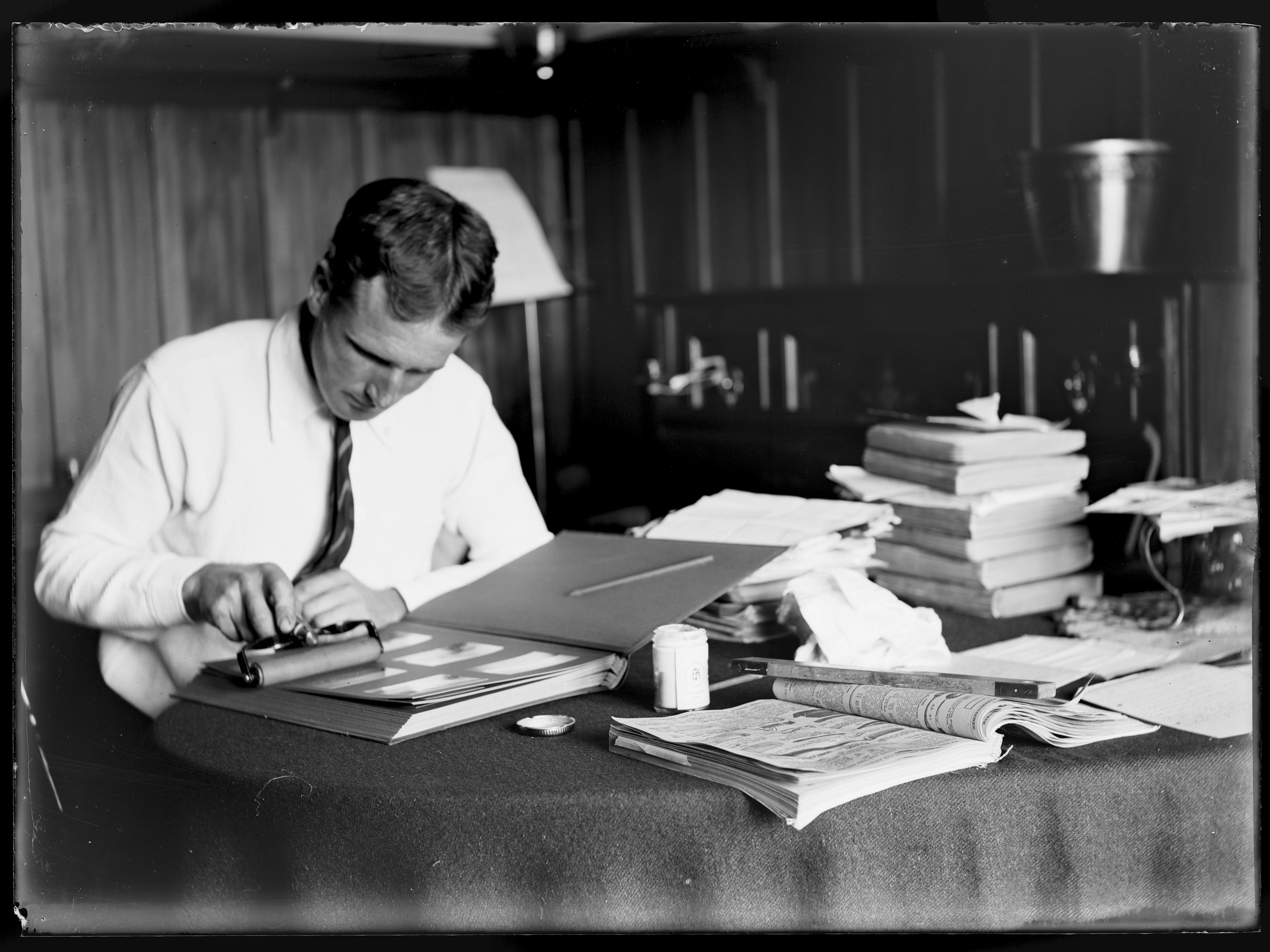 The photographic record, 17 February 1918, North Island, by Leslie Adkin. Gift of G. L. Adkin family estate, 1964. Te Papa (B.022811) Black and white photo of a man putting a photo in a photo album