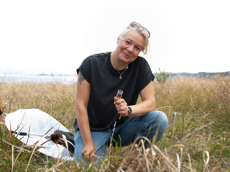 Julia kneeling in the grass, she has a net by her side