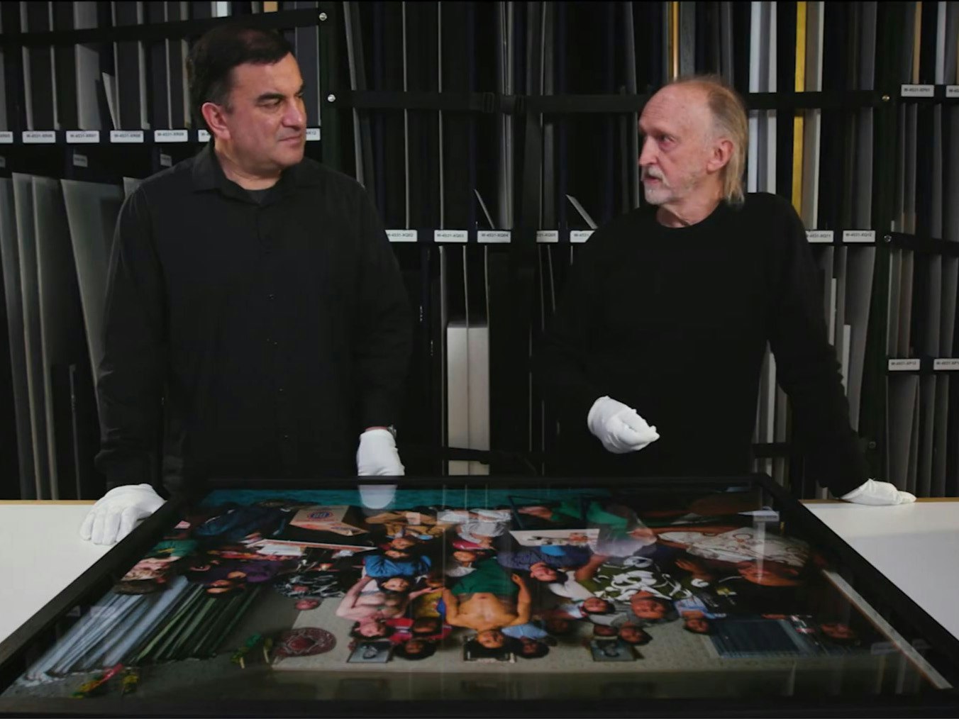 Still from Photographing Sāmoan Tatau (tattoo). Te Papa Two men standing in front of a photograph, both wearing white gloves