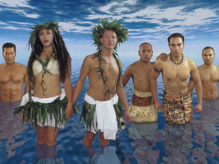 Like Our Ancestors poster, 1998, New Zealand, by New Zealand AIDS Foundation, Arjan Hoeflak, Mariano Vivanco, Harold Samu. Gift of New Zealand AIDS Foundation, 2019. Te Papa (GH025369) Crop from a poster featuring six people in traditonal Pacific clothing standing in a vast expanse of water with a vast sky above them.