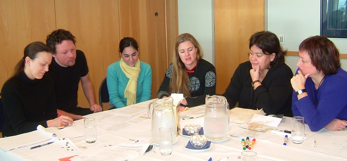 Six people sitting around a table discussing documents