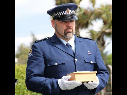 Constable Craig Bennett holds the final remains of Jessie Marguerite Fendall, which were reunited with her body on Friday. Photo by New Zealand Police A man in a police uniform holding a small wooden box in gloved hands
