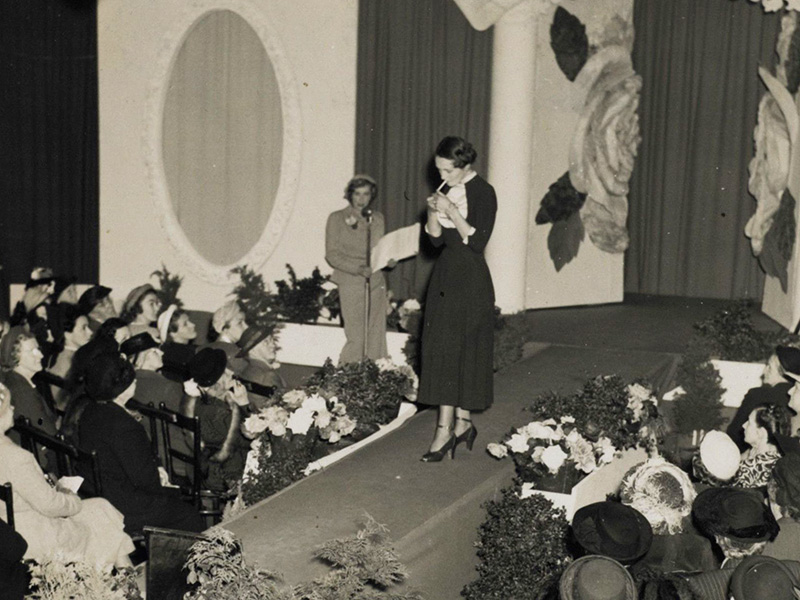 A black and white photo of a woman lighting up a cigarette on the catwalk