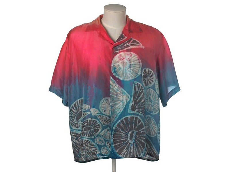 ‘Opihi Aloha shirt, Kupu A'e; manufacturer(s), 2017, Hawaii. Te Papa (FE013086) A purple and dark button-down shirt with grey and black batik patterns and circles printed on it