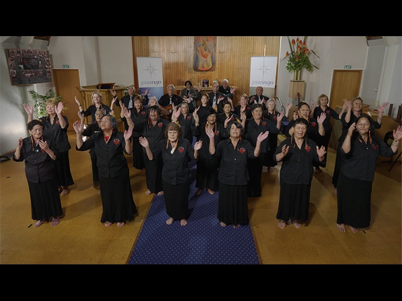 Video still from Taikura Kapa Haka 2021. Te Papa People standing in a group dancing in formation