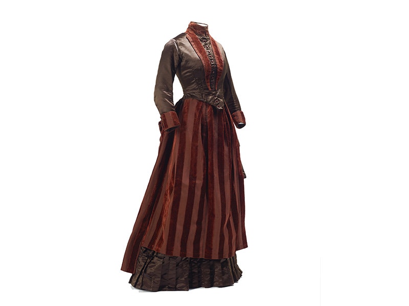 ma_i358195-dark-brown-satin-and-velvet.jpg A brown silk and velvet 1880s dress with a white background.