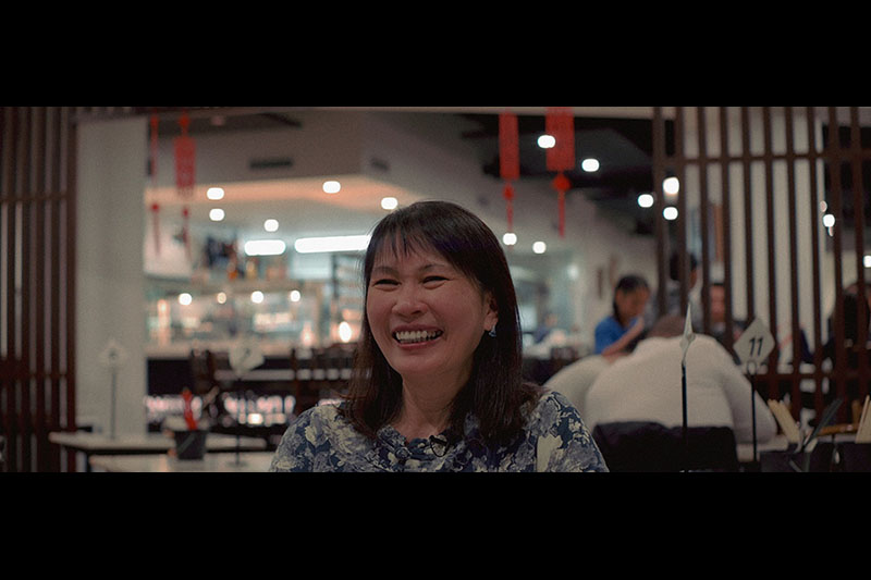 A woman smiles as she talks to an interviewer off-screen