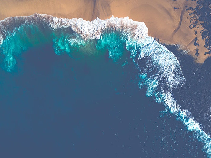 Pūpūkea, Hawaiʻi, from above. Photo by Marek Okon via Unsplash An aerial shot of waves breaking on a beach