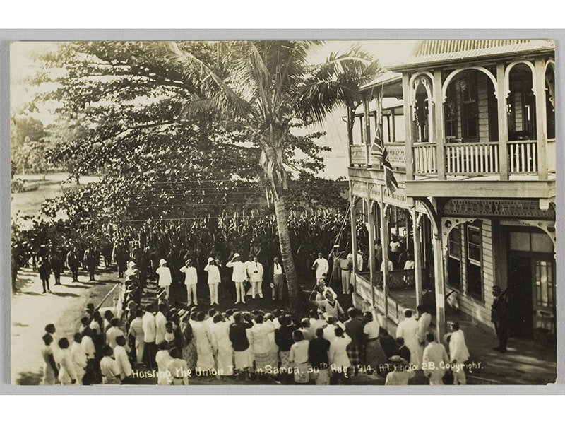 Postcard, 'Hoisting the Union Jack in Samoa. 30th Aug 1914.', 1914, Sāmoa, by Alfred James Tattersall. Purchased 2011. Te Papa (GH023108) A sepia photo of people in uniform in Sāmoa hoisting a flag