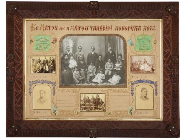 Ko mātou me ā mātou tamariki, mokopuna hoki about 1900. Photographer unknown. Gelatin silver and opaltype prints, hand decorated card, carved wood frame. On loan from private collection A black and white family portrait from the 1900s