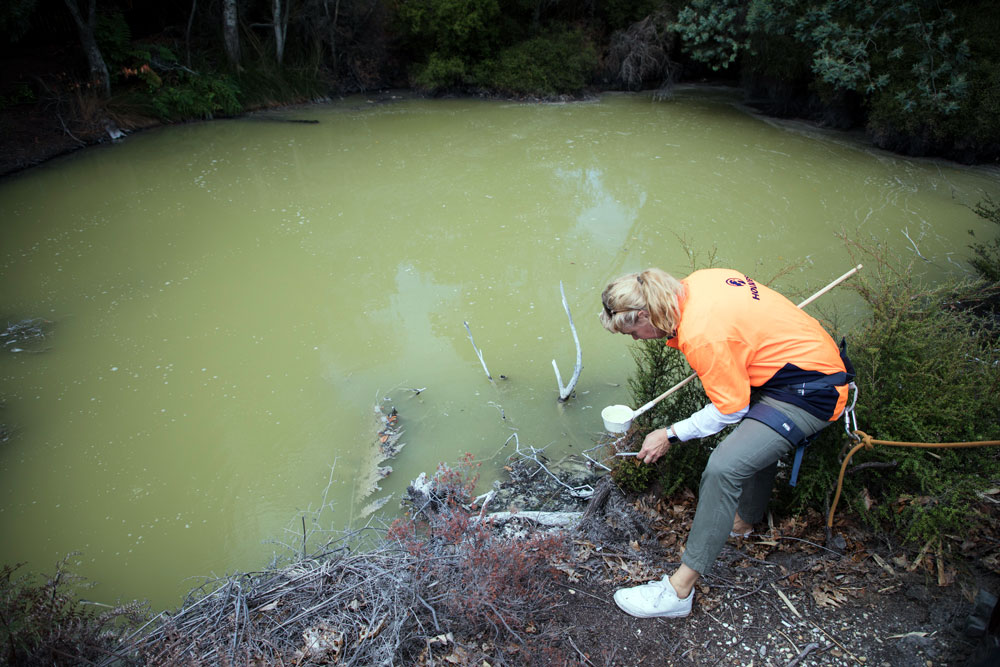 A woman near a pond with a net and wearing harness gear