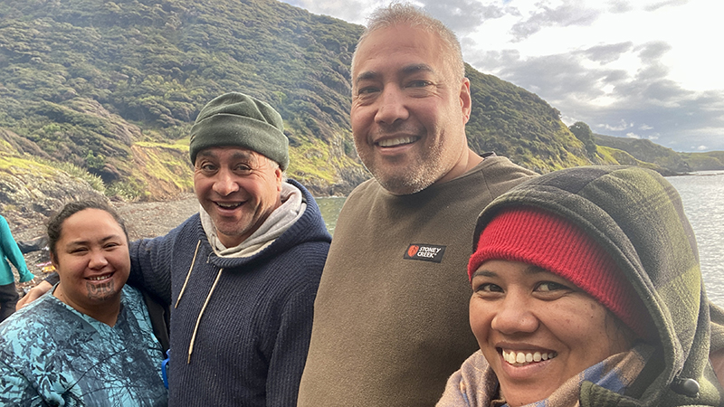 Four people standing closely together smiling at the camera