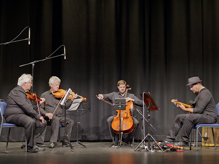 Three people on stage playing instruments