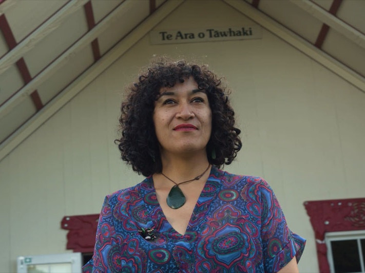 Still from Ngā Taonga Tuku Iho #5: Kaihahu Mahara, 2022, by Pikihuia Haenga and Elise Lanigan. Image courtesy of Kahu Kutia A woman stands in front of a marae looking into the camera