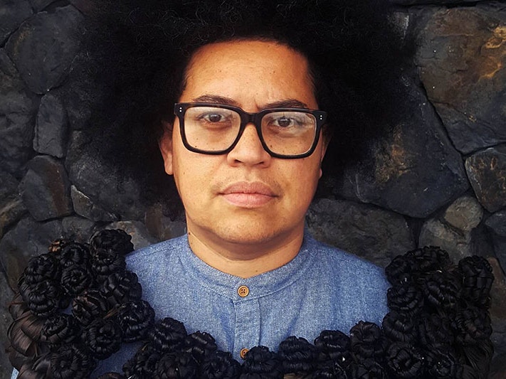 Luisa Tora, with her salusalu. Photo by Sangeeta Singh, courtesy of Luisa Tora Portrait of a woman, wearing a black salusalu – necklace – made to look like a wreath of flowers