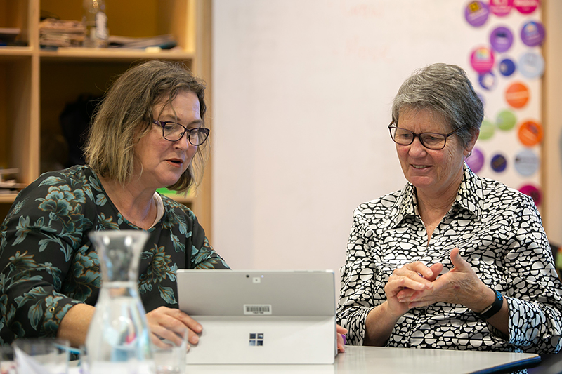 Two women looking at a laptop and discussing what they're seeing