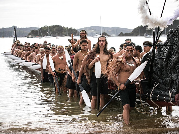 Waka taua at Waitangi, 2020. Photo courtesy of Te Rawhitiroa Bosch A group of Māori men lift a waka onto the shore