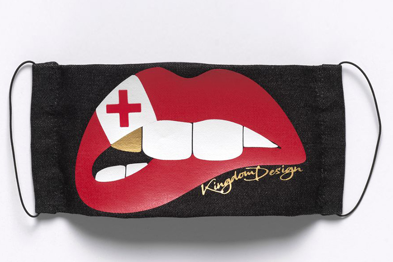 a black facemask with the image of a mouth with red lips, white teeth and a single gold tooth