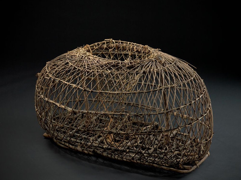 Tāruke Koura (crayfish trap). wood, maker unknown. Purchased 1913. Te Papa (ME003080) A woven wooden crayfish trap photographed with a black background.
