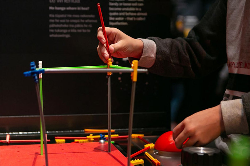 Close up of hands building a structure with long sticks and end-pieces