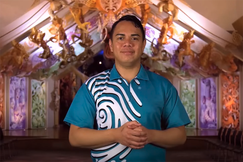 A man standing in front of a carved building with his hands clasped in front of him.