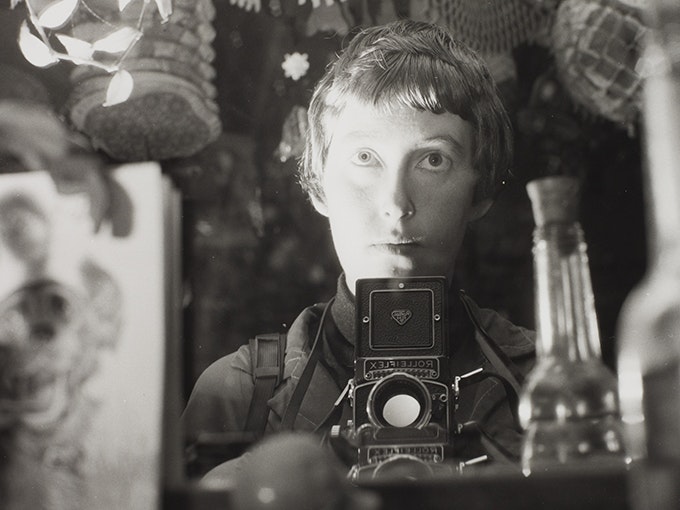 Ans Westra, Self portrait, 1964, black and white photograph, gelatin silver print. Te Papa (O.042837) A woman with a camera is taking a self portrait in a mirror.