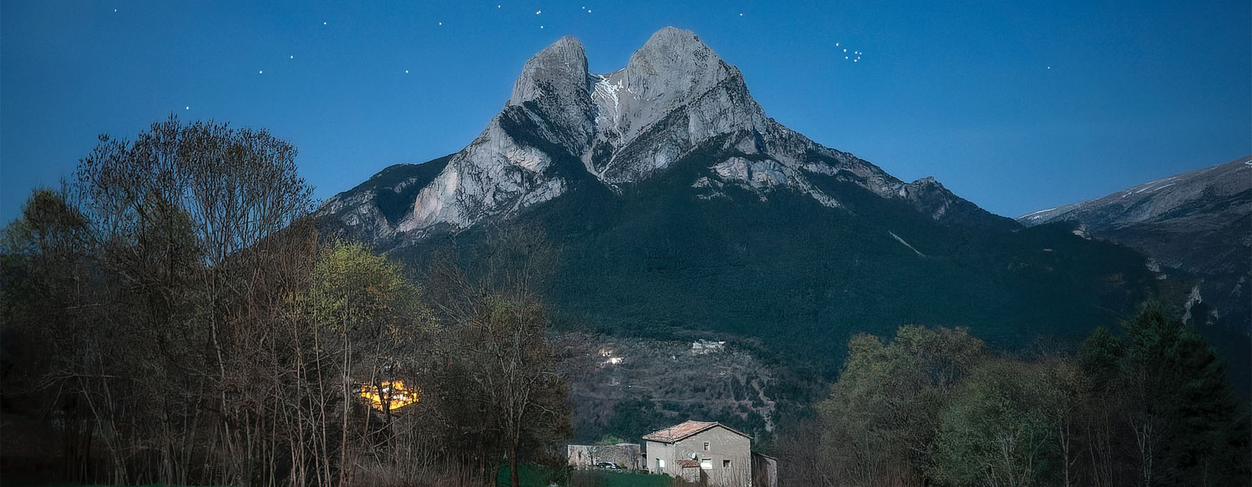 View of the Matariki cluster in the northern hemisphere above a mountain. In the foreground is a horse resting and a rural house