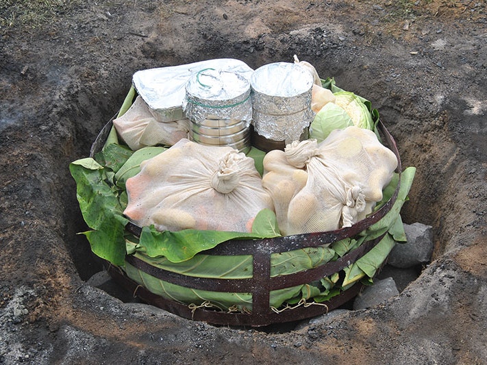 Hāngi, 2014. Photo by Francesco Scotti. CC BY-NC-ND 2.0 Food wrapped up, in a pit, ready to be covered and cooked in a hāngi