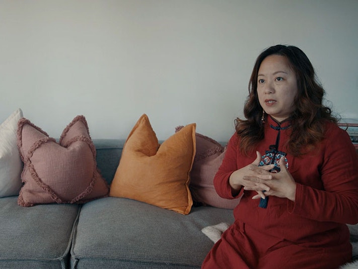 Eva Chen, 2022. Photo by Julie Zhu. Te Papa Eva sits on a couch talking to a person out of shot