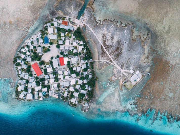 Aerial shot of Fakaofo, Tokelau, 2017. Photo by Andrew Matautia. Te Papa O.047897 Aerial photo of an island showing dense housing, with the sea level around the island low
