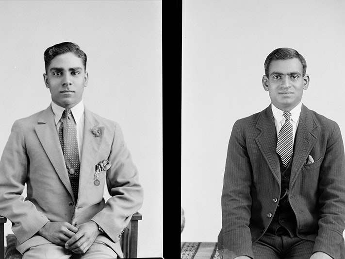 a split black and white image of two sitting men posing for a studio photograph.