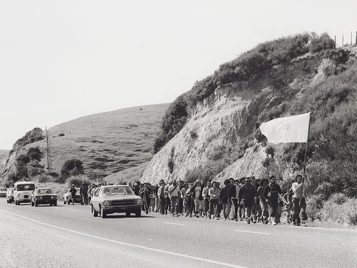Ans Westra, Māori Land March, 1975, gelatin silver print. Purchased 1993 with New Zealand Lottery Grants Board funds. Te Papa (O.009448/01) Black and white photo of a large group of people marching alongside a rural road. The person at the front is carrying a large flag