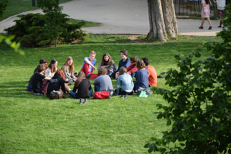 Group of young people sitting in a circle in a park